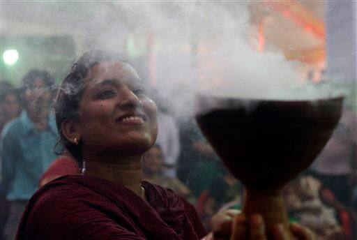 A Hindu woman holds a pot of holy smoke while dancing as a part of religious rituals for offering prayers during Hindu festival Durga Puja in Mumbai.