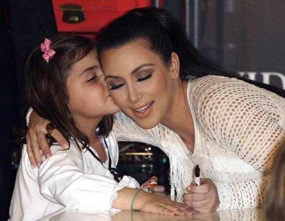 Kim Kardashian receives a kiss from a girl during a launch of her fashion accessory range at a department store in Sydney. 