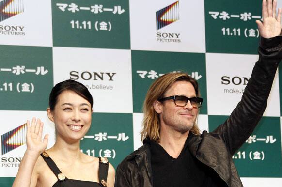 Actor Brad Pitt and Japanese actress Kazue Fukiishi waves during a press conference of his latest film 'Moneyball' in Tokyo.