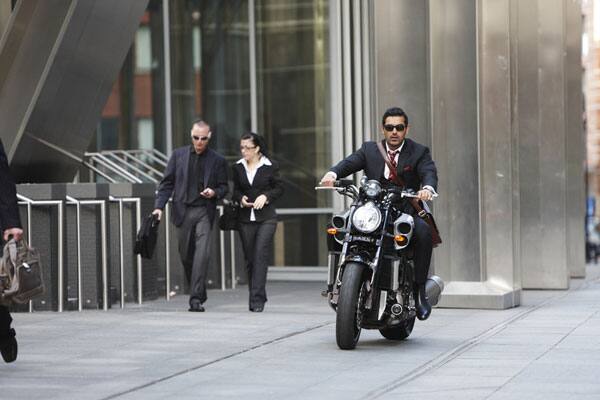 John riding on a bike looking macho in a still from the film.