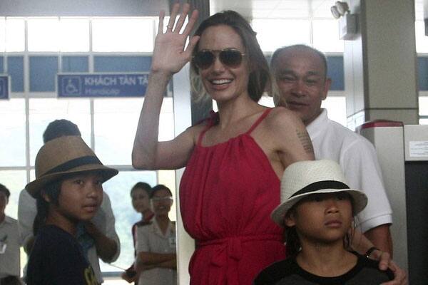 Hollywood actress Angelina Jolie waves to the media as she stands with her adopted sons Pax Thien from Vietnam and Maddox  from Cambodia at a security check point before leaving Con Dao island.