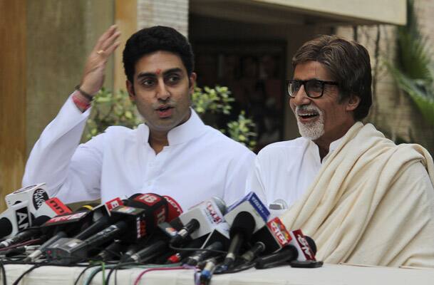 Amitabh Bachchan, right, laughs as his son Abhishek Bachchan speaks during a press conference in Mumbai.