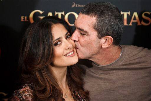 Spainish actor Antonio Banderas, right, kisses actress Salma Hayek, left, while promoting 'Puss in Boots' US animated film, in Madrid.