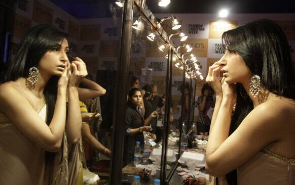 A Pakistani model applies make up during Fashion Week, in Karachi.