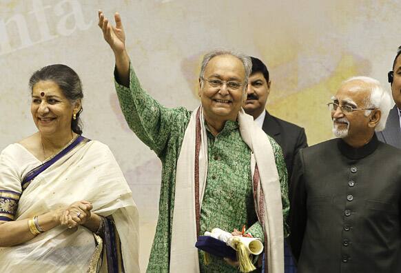 Bengali film and theater actor Soumitra Chatterjee, center, waves after receiving the Dadasahab Phalke Award for the year 2011, as Indian Vice President Hamid Ansari, right, and Indian Minister for Information and Broadcasting Ambika Soni look on, during the 59th National Film Award in New Delhi.