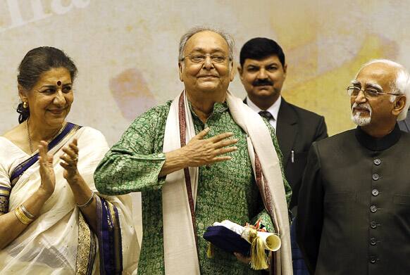 Bengali film and theater actor Soumitra Chatterjee, center, waves after receiving the Dadasahab Phalke Award for the year 2011, as Indian Vice President Hamid Ansari, right, and Indian Minister for Information and Broadcasting Ambika Soni look on, during the 59th National Film Award in New Delhi.