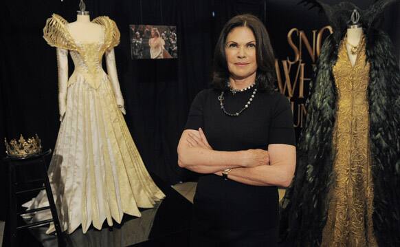 Photo shows Academy Award-winning costume designer Colleen Atwood posing with two costumes from the film 