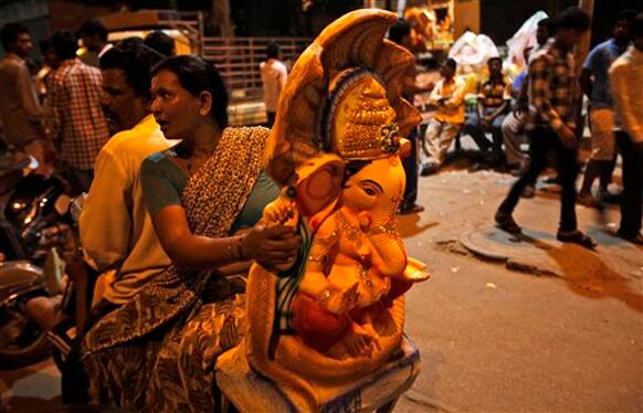 An Indian woman sits pillion on a bike carrying an idol of elephant-headed Hindu God Ganesha in Hyderabad, India, Monday, Sept. 17, 2012. The ten-day Ganesh  festival begins on Sept. 19 and ends with the immersion of Ganesha idols in water bodies on the last day. 