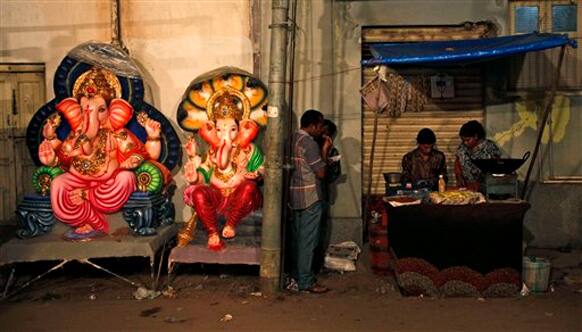 Idols of elephant-headed Hindu God Ganesha are kept for sale beside a stall selling snacks in Hyderabad, India.