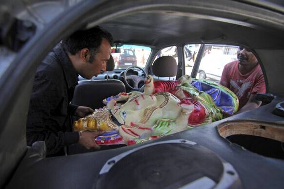 Hindu devotees load an idol of Hindu God Ganesha into a car to take home, in Jammu.