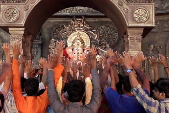 Devotees raise their hands as they pray in front of an idol of Hindu God Ganesha in Ahmadabad.