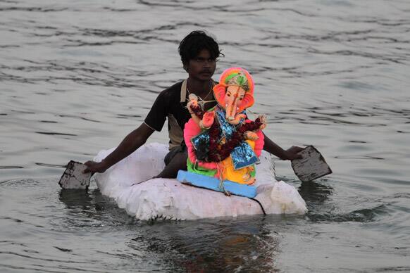 A man carries an idol of Hindu god Ganesha on a makeshift raft to immerse it in the river Sabarmati during the Ganesh Chaturthi festival in Ahmadabad.