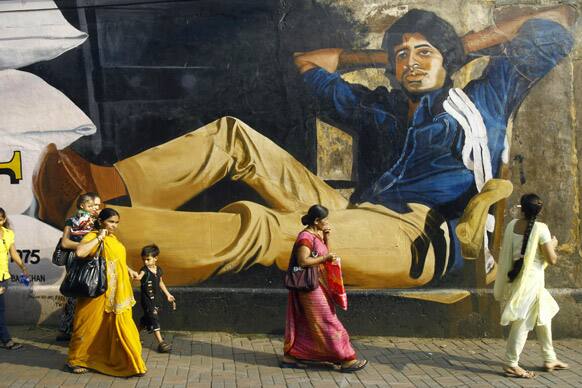 People walk past a giant portrait of Bollywood's biggest star Amitabh Bachchan painted on a wall, a day ahead of his 70th birthday, in Mumbai.