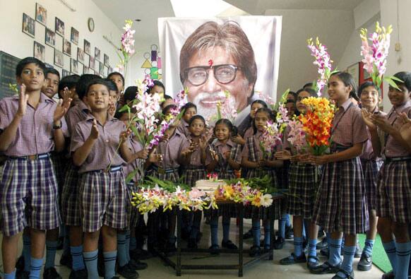 Schoolchildren stand in front of a portrait of Bollywood's biggest star Amitabh Bachchan, at an event a day ahead of his 70th birthday, in Mirzapur.