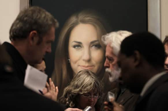 Members of the media talk to artist Paul Emsley, center right, in front of his newly-commissioned portrait of Kate, Duchess of Cambridge, on display at the National Portrait Gallery in London.