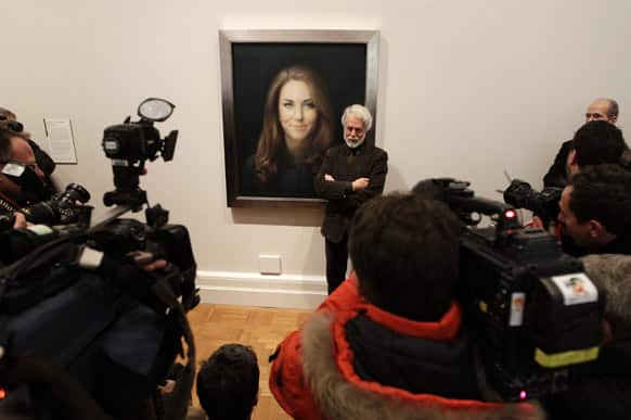 Artist Paul Emsley poses for photographers next to his newly-commissioned portrait of Kate, Duchess of Cambridge, on display at the National Portrait Gallery in London.