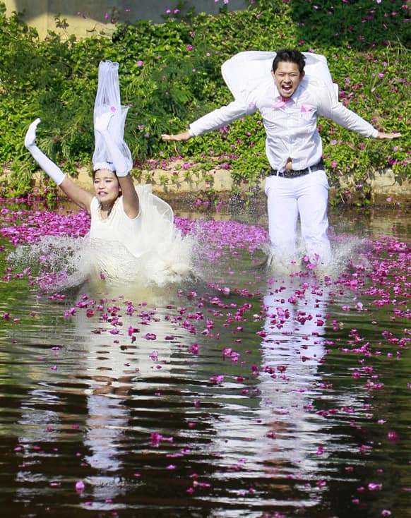 Varutton Rangsitwong, left, and Prasit Rangsitwong jump into the water during a part of an adventure-themed wedding ceremony in Prachinburi province, Thailand, on the eve of Valentine's Day.
