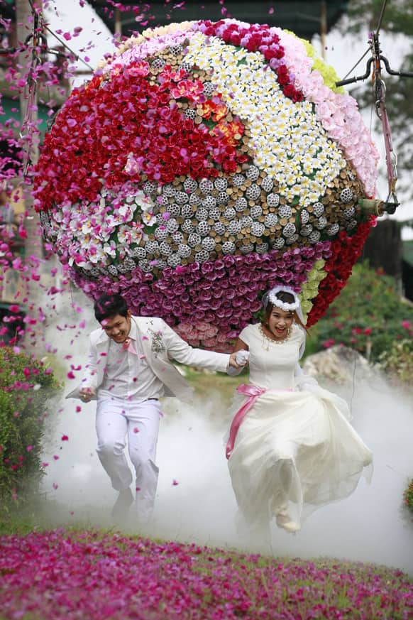 Prasit Rangsitwong, left, and Varutton Rangsitwong run away from a giant flower ball as a part of an adventure-themed wedding ceremony in Prachinburi province, Thailand, on the eve of Valentine's Day.