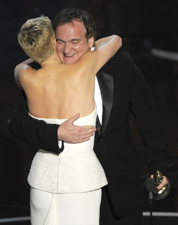 Actress Charlize Theron, left, embraces Quentin Tarantino as she presents him with the award for best original screenplay for