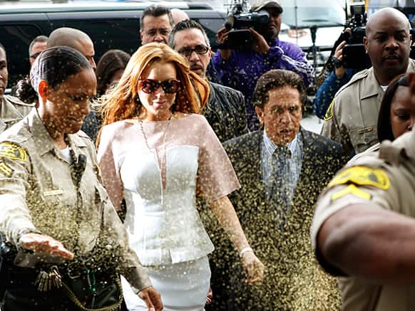 Actress Lindsay Lohan is showered with gold glitter, second left, as she walks with her attorney Mark Heller, at Los Angeles Superior court.