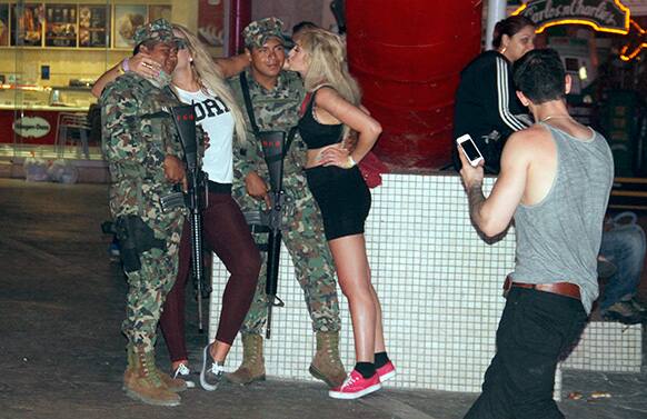 Spring Break revelers pose for photos with Mexian navy marines patrolling the night club area in the resort city of Cancun, Mexico.
