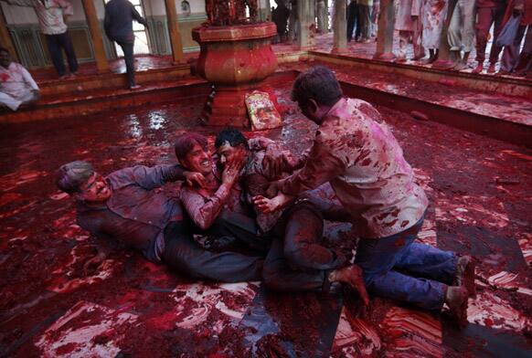 Hindu men joke as they wrestle on the ground during prayers at the Ladali or Radha temple before the procession for the Lathmar Holy festival, the legendary hometown of Radha, consort of Hindu God Krishna, in Barsana.
