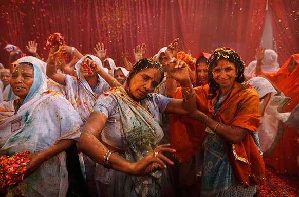 Indian widows dance and throw flowers during Holi celebrations, or the festival of colors, at an event organized by the NGO Sulabh at the Meera Sahbhagini Ashram in Vrindavan.