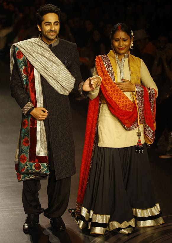 Bollywood actor Ayushmann Khurrana, left, along with health worker and activist Sunita Sutar displays creations by Vikram Phadnis during the Lakme Fashion Week in Mumbai.