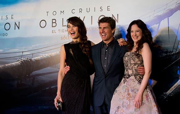 US actor Tom Cruise, center, embraces actress Olga Kurylenko, left, and Andrea Riseborough as they posse for pictures during a presentation to promote the film