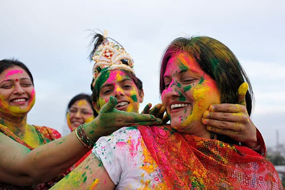Indian women smear colors on each others faces as they celebrate