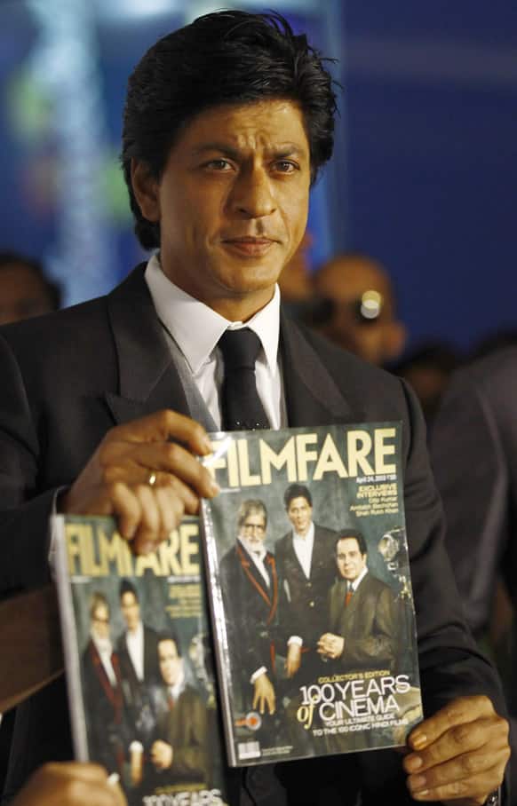 Bollywood star Shahrukh Khan poses with the copies of the Filmfare magazine after unveiling it to celebrate the 100th year anniversary of Indian cinema, at an event in Mumbai.