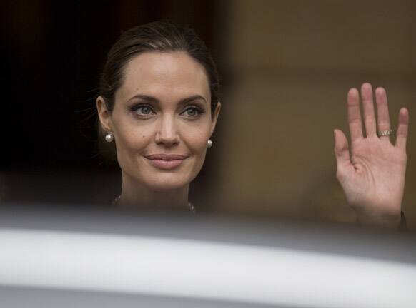 Angelina Jolie waves to the media as she leaves a G8 Foreign Ministers meeting on sexual violence against women in London.