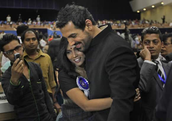 Bollywood actor John Abraham hugs fellow actor Usha Jadhav during the National Film Awards 2012, in New Delhi. Abraham's debut production