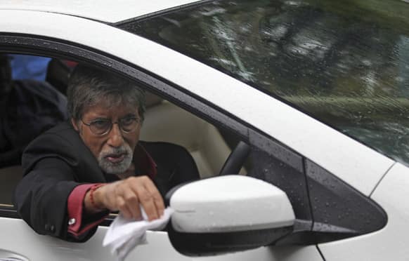 Amitabh Bachchan wipes rain drops from the rear view mirror of a car during a commercial shoot at the film city in Mumbai.