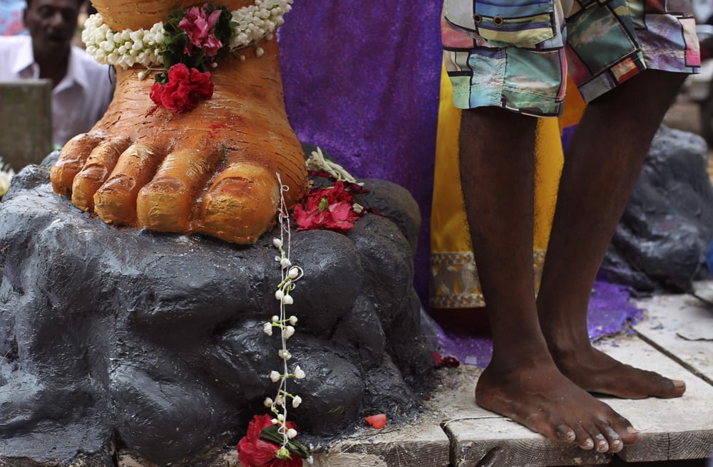 A devotee stands near a huge idol of the Hindu god Ganesh as it is transported to a place of worship in Mumbai.