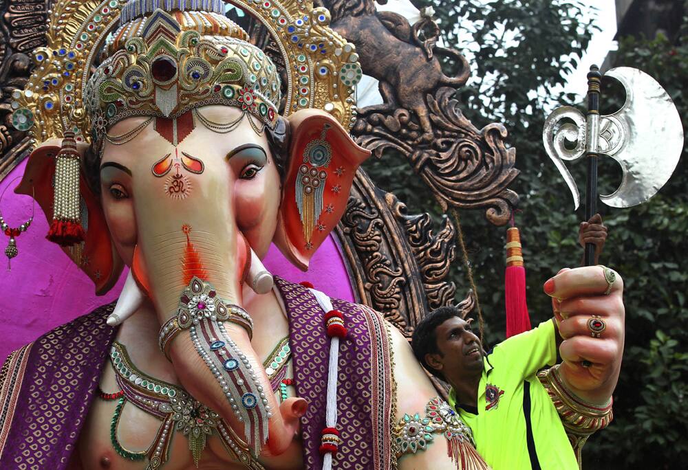 A volunteer tries to adjust the axe of an idol of the Hindu god Ganesh as the same is transported to a place of worship in Mumbai.