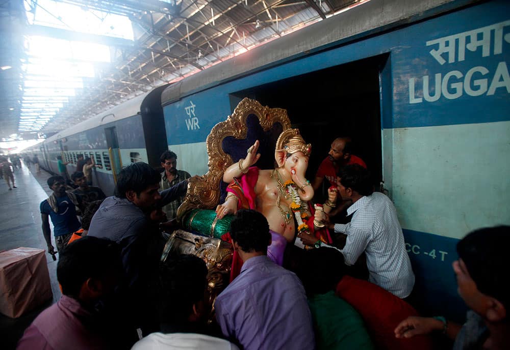 A clay idol of elephant headed Hindu god Ganesh is carried onto a passenger train before being transported to a place of worship in Mumbai.