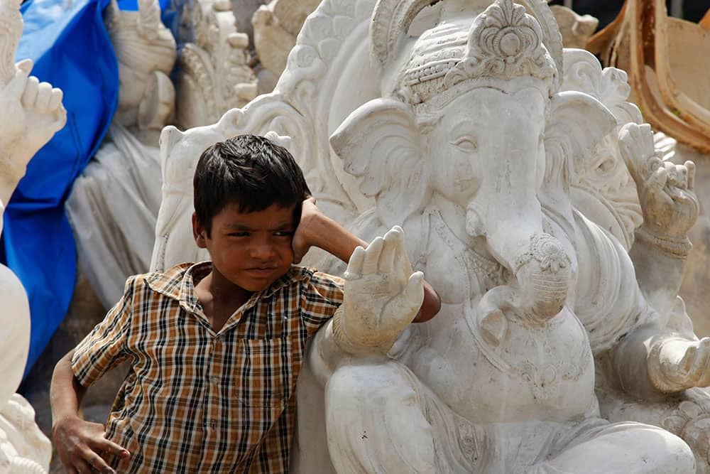 An Indian boy stands amid idols of elephant-headed Hindu god Ganesh being prepared ahead of Ganesh Chaturthi festival at a workshop in Hyderabad.