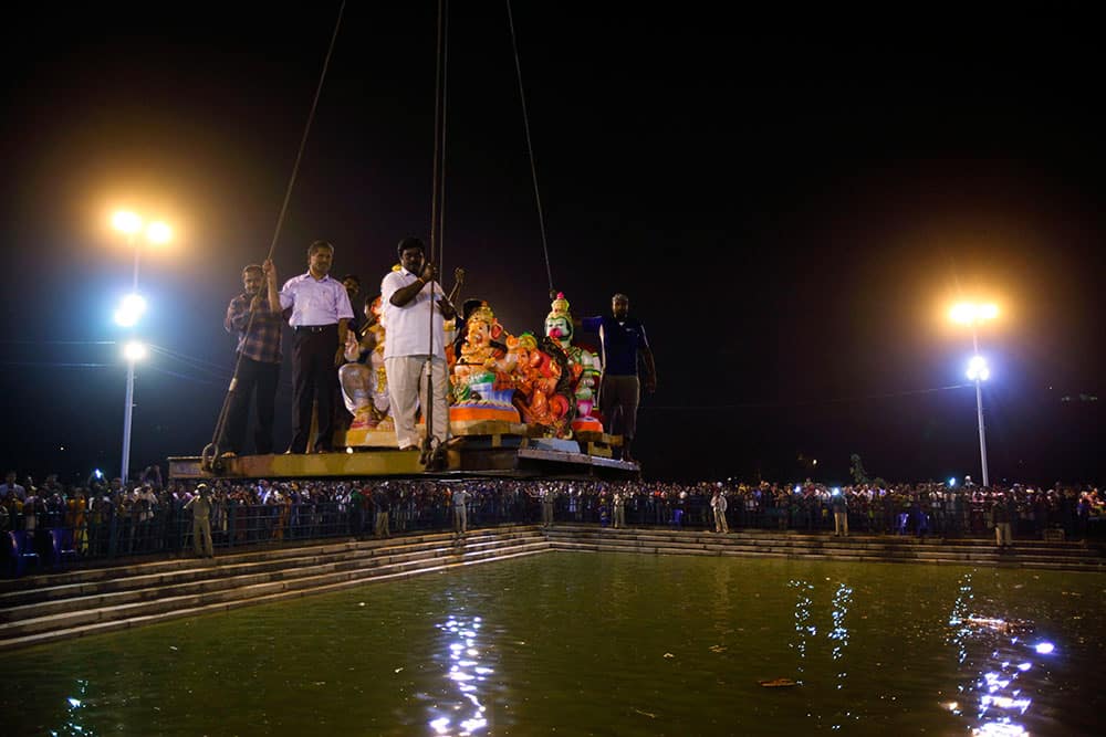 Worshippers watch as idols of elephant-headed Hindu god Ganesha are carried by a crane for immersion in a pond during Ganesh Chaturthi festival celebrations in Bangalore.