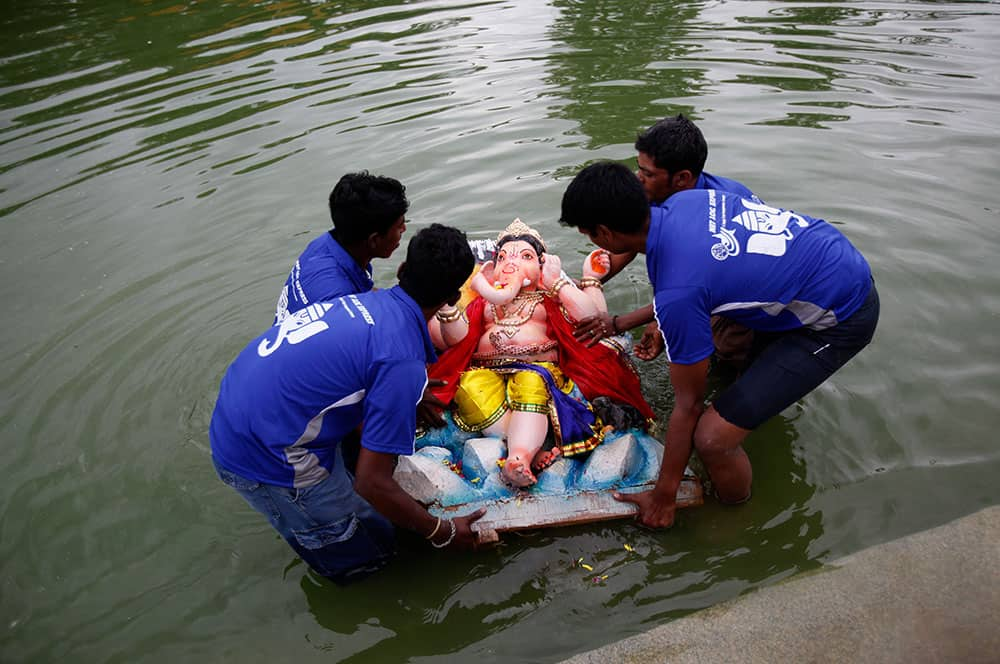 Volunteers prepare to immerse an idol of elephant-headed Hindu god Ganesha in a pond during Ganesh Chaturthi festival celebrations in Bangalore.