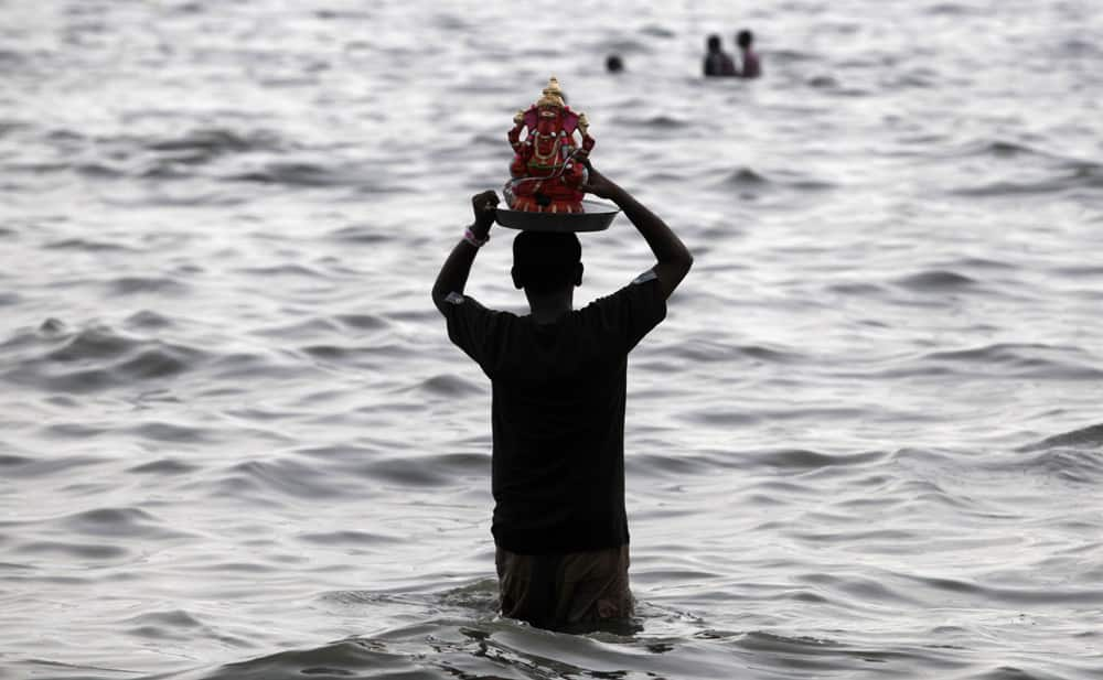 A devotee prepares to immerse an idol of elephant-headed Hindu god Ganesha in the Arabian Sea during Ganesh Chaturthi festival celebrations in Mumbai.