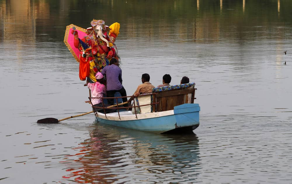 Hindu devotees use a boat to immerse an idol of elephant-headed Hindu god Ganesha in the Gomati River during Ganesh Chaturthi festival celebrations in Lucknow.