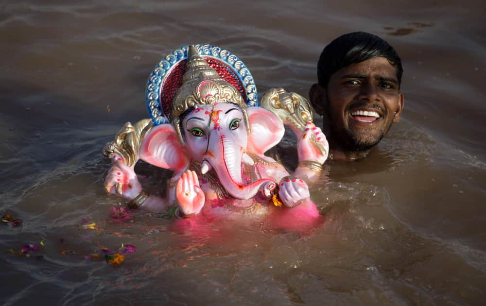 A volunteer smiles as he immerses an idol of elephant-headed Hindu god Ganesha in an artificial pond, specially set up for the immersion of idols to prevent pollution in the river Sabarmati, in Ahmadabad.