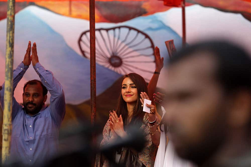 Miss Universe Olivia Culpo, center, applauds inmates as she stands before a painting of the Indian flag during a visit to the Tihar Jail in New Delhi.