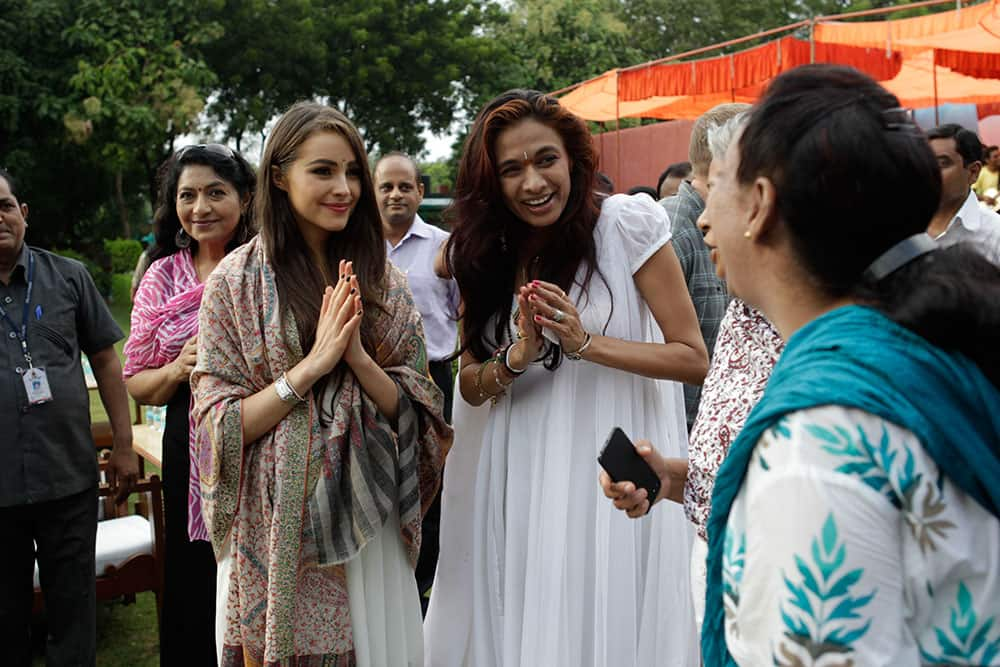 Miss Universe Olivia Culpo, center left, accompanied by designer Sanjana Jon, center right, greets an inmate during a visit to the Tihar Jail in New Delhi.