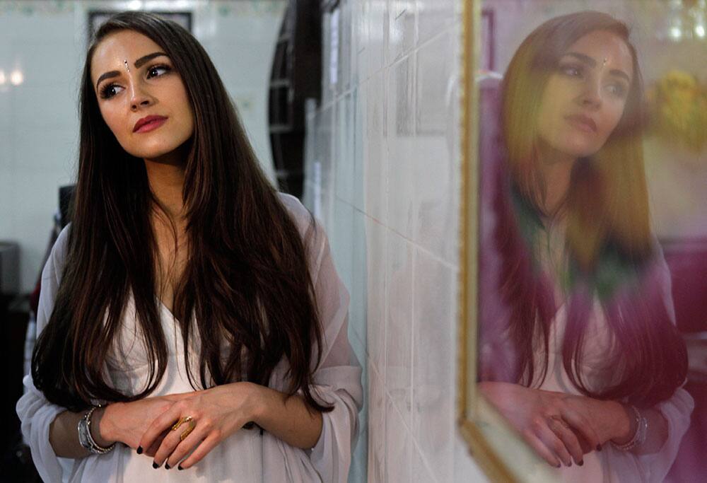 Miss Universe Olivia Culpo, is reflected on the glass of a Lord Buddha painting displayed on a wall during a visit to the Tihar Jail in New Delhi.