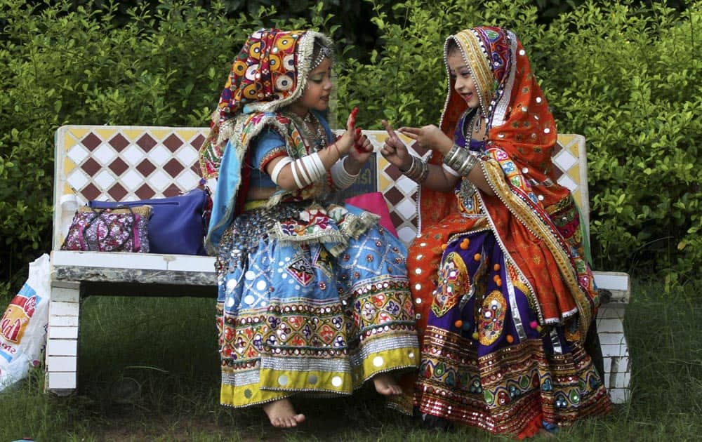 Young Indian girls dressed in traditional attire play with each other as others practice Garba, a form of dance from the west Indian state of Gujarat.