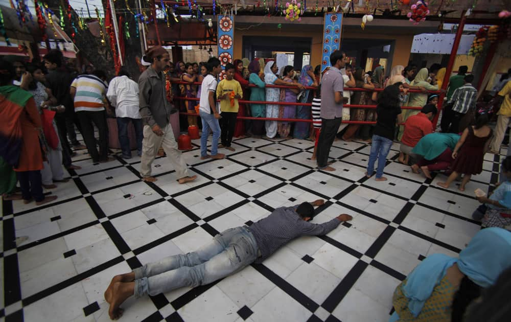 A Hindu devotee prostrates as others stand in a queue to offer prayers at a Hindu goddess Kali temple on the second day of the Navratri festival in Jammu.