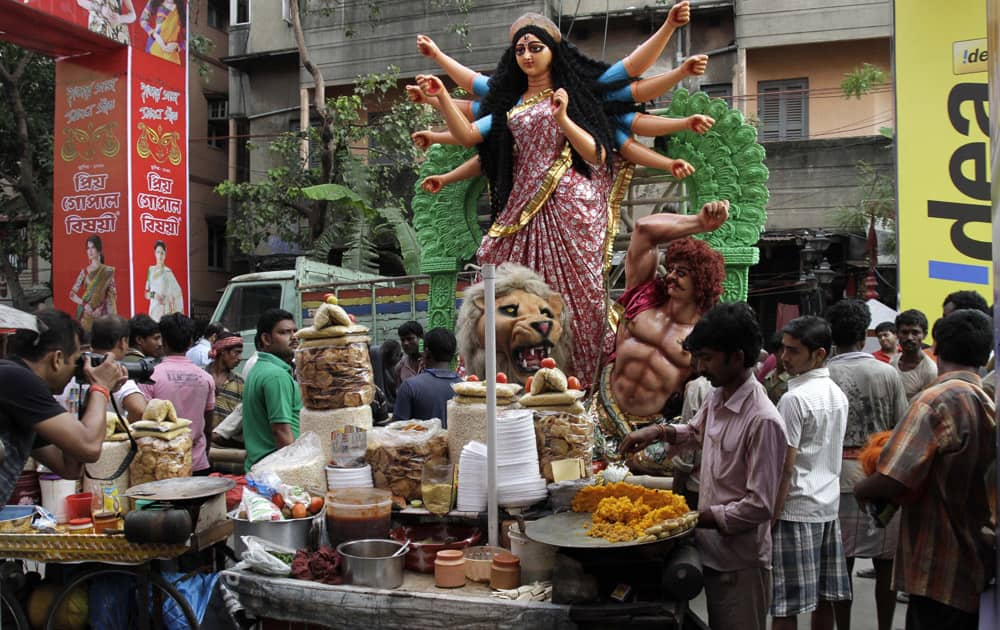 An idol of Hindu goddess Durga is transported past a snack vendor to a venue of worship in Kolkata.