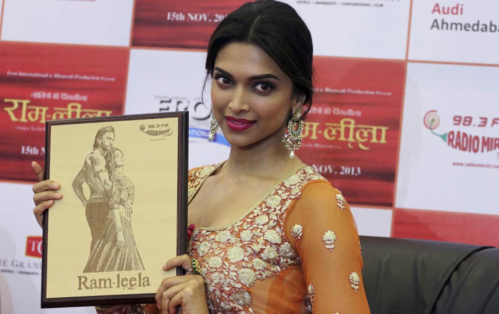 Deepika Padukone displays a photo frame presented to her with a portrait of her and actor Ranveer Singh during a press conference held to promote her new Hindi film “Ramleela” in Ahmadabad.